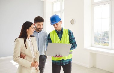 Foreman genç gülümseyen ev sahiplerine dizüstü bilgisayarda boş beyaz odada duran yeni dairenin tasarımı ya da onarımı projesini gösteriyor. İç dekorasyon hakkında müteahhitle görüşeceğim. Taşınma konsepti.