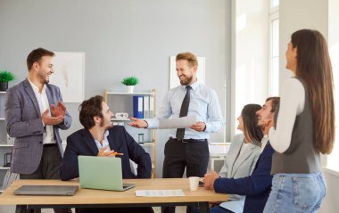 Takım toplantısı, konferans ya da sunum sırasında ofiste birlikte çalışan dost canlısı iş adamları. Gösteri camiası, takım çalışması ve iş yerinde profesyonel işbirliği.