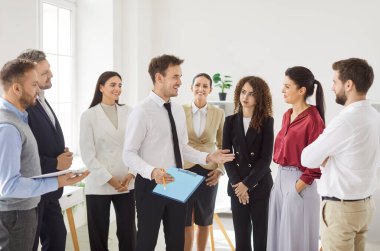 Olumlu bir grup iş adamı iş toplantısı sırasında ayakta durup erkek meslektaşlarını dinliyor. Profesyonellerden oluşan bir ekip fikirleri tartışıyor, beyin fırtınası yapıyor, ortak bir proje üzerinde çalışıyor..