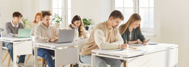 Eğitim ve öğrenim kavramı. Bir grup üniversite öğrencisi ya da lise öğrencisi dizüstü bilgisayarlarıyla masada oturuyor, modern teknolojilerle aynı sınıfta okuyor, iyi bilgi ediniyorlar.