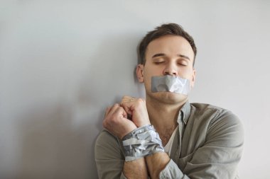 Erkek mağdur suçu, ağzı ve elleri bantlı adam sessiz kalmayı sürdürüyor acı çekiyor, yaralı, suç, kaza, çaresiz ve pasif, insani kötü muamele, fiziksel, zihinsel ya da duygusal zarar