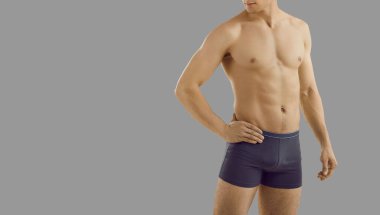 Gri stüdyo arka planında izole edilmiş iç çamaşırlı yakışıklı seksi erkek mankeni. İç çamaşırı giymiş kaslı bir erkek, reklam şortu giyiyor. Moda ve tarz. Boşluğu kopyala.