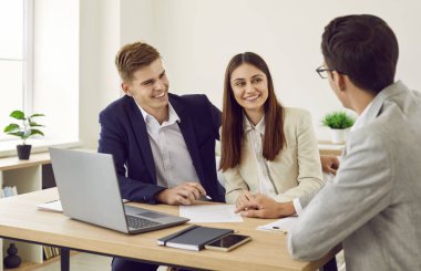 Genç evli çift emlakçı ya da tefeciyle buluşuyor. Mutlu erkek ve kadın müşteriler ofis masasında oturup onlara kağıt sözleşmesi sunan emlakçıya veya kredi müdürüne gülümsüyorlar.