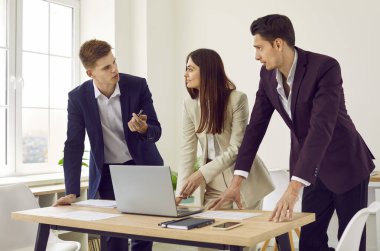 Bir grup iş arkadaşı modern ofiste birlikte çalışmak için dizüstü bilgisayar kullanmayı tartışıyorlar. Genç erkek ve bayan iş arkadaşları birlikte çalışarak yeni projeyi tartışıyor. İş ortaklığı kavramı.