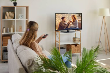 Tembel bir haftasonu genç bir kadının arka görüntüsü evde kanepede dinlenir ve televizyon izler. Oturma odasındaki kadın kiracı ya da kiracı televizyonda film izlemekten zevk alıyor. Eğlence, rahatlama konsepti.