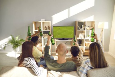 Televizyonda futbol maçı izleyen arkadaşlar. Oturma odasındaki kanepede oturan, TV 'de futbol seyreden ve bira içen bir grup genç kadın ve erkek hayranın arkasından bakın.