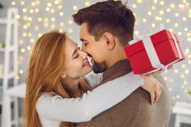 Mutlu romantik anlar. Sevgililer Günü 'nde birbirlerine hediye verdikten sonra sarılıp öpüşen iki sevgili. Birbirini seven bir çift sıcak bir odada kutlama yapıyor. Şefkat ve sevgi kavramı.