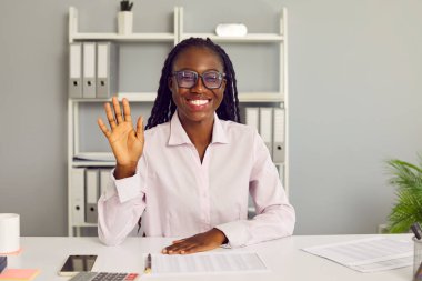 Portre mutlu, Afro-Amerikalı iş kadını. Ofis masasında kameranın önünde oturuyor. İnternetteki iş toplantısına video konferansından başlıyor.