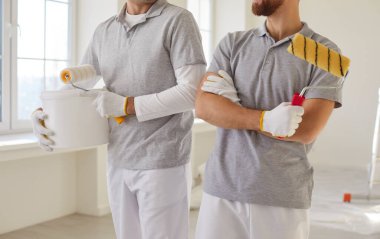 Elinde kova ve boya rulosu tutan yüzü olmayan erkek ressamlar. Tadilat dairesi yapmakla, takım olarak çalışmakla, duvarları yenilemekle meşguller. Dekorasyon işi yapan iki tamirci.