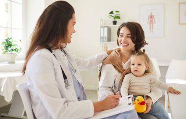 Genç anne ve babası tatlı bir bebekle oturuyor ve gülümseyen dost canlısı çocuk doktoru aile doktoruyla klinikte istişarede bulunuyor ve tıbbi muayeneden sonra tavsiyeleri dinliyor..