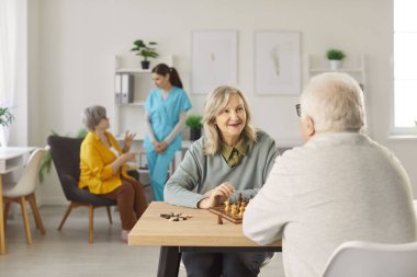 Huzurevinde aynı masada oturup satranç oynayan mutlu iki yaşlı hasta. Boş zaman, eğlence ve zihinsel bağlılık, oyun boyunca arkadaşlığı ve eğlenceyi teşvik etmek.