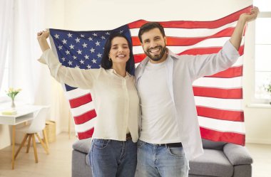 Mutlu gülümseyen Amerikan halkı aşk ülkesi, vatansever çift, gururlu erkek, omuzlarının üzerinde ABD bayrağı taşıyan kadın, bayramı kutluyor, Amerikan Vatanseverlik Günü, kazanma gururu.