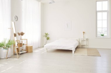 Moda mobilyaları, bitkiler, halı, yatak ve şık ev dekorlarıyla İskandinav tarzında modern çağdaş ev yatak odasının fotoğrafı. İç tasarım kavramı.