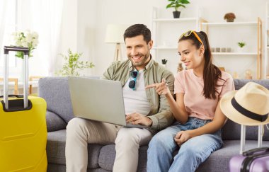 Uçak bileti, otel rezervasyon hizmeti internetten, yeni evli çiftin seçtiği bavullar valizler, tekerlek bavulu, plaj şapkası, turizmden, seyahatten, balayı planından keyif almaya hazır.