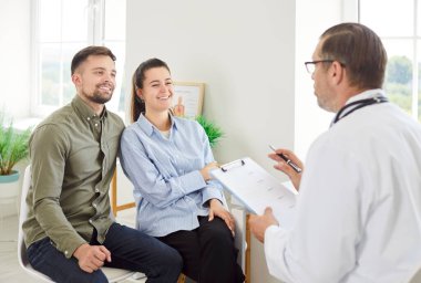 Doktor, olumlu bir aile çiftine hastanede hamilelik planlaması hakkında danışmanlık yapar. Sağlık görevlisi, çiftin gerekli sağlık kontrolü ve desteği almasını sağlar..