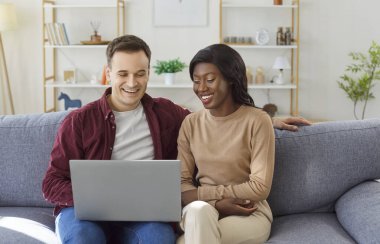 Mutlu aile çiftimiz evlerinde kanepede keyfine bakıyor, birlikte internet eğlencesine dizüstü bilgisayar kullanıyorlar, her an kahkaha ve neşe dolu bir ortamda rahatlıyorlar..