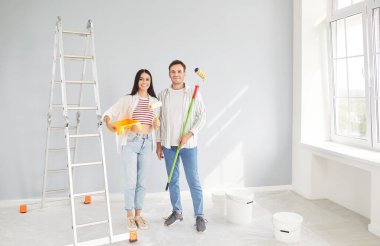 Mutlu ve neşeli bir çiftin portresi. Yeni evin tadilatı sırasında bir arada duruyorlar. Resim, inşaat, dekorasyon ve kişisel bir yaşam alanı yaratmanın keyfi..