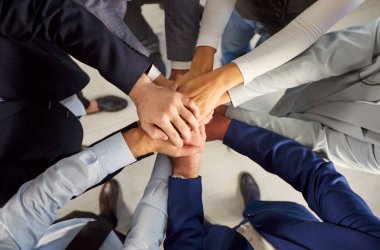 Resmi giysiler içinde kollarını birleştiren iş adamlarının üst görüntüsünü kapat. Bir grup şirket çalışanının el yığını. Birlik, ortaklık ve takım çalışması kavramı.