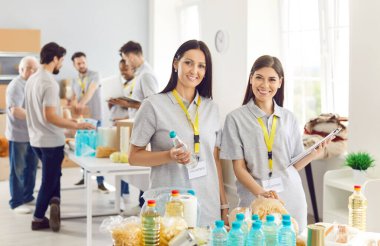 İki neşeli genç bayanın portresi, hayır yemeği için yiyecek alışverişi yapıyor. İnsanlar gıda bankasında gönüllü olarak hayır kurumunda çalışıyor. İnsani yardım