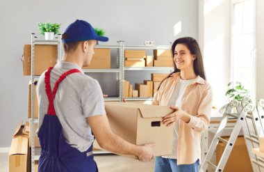 Depoda lojistik ya da dağıtım merkezindeki kadın küçük işletme sahibiyle çalışan teslimat işçisi bir müşterinin siparişini hazırlıyor. Stok envanteri.