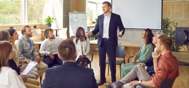 Bir grup farklı iş arkadaşı bir çemberin içinde oturup bir toplantı odasında finans raporuyla erkek meslektaşlarını dinliyorlar. Şirket büyümesi hakkında iş eğitimi alan iş adamları.