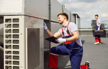Mavi örtü giyen, havalandırma, havalandırma, havalandırma ya da havalandırma sistemini tamir eden mutlu gülümseyen erkek teknisyen. Klima tamircisi servisi açık havada.