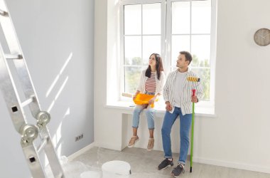 Genç çift mutlu ressamlar yeni bir daire inşa etme fikri, boya fırçasıyla duvar boyama, odanın taşınmasını tamamlama, bina onarımı, yenileme, yenileme, birlikte yeni bir hayata başlama