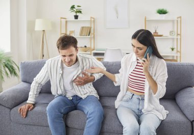 Göğüs ağrısı çeken genç bir adam kalp krizi geçiriyor. Oturma odasındaki koltukta eşiyle oturuyor. Kadın, kocasına cep telefonuyla acil durum ambulansını arıyor. Sağlık ve Tıp Konsepti.
