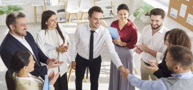 İş adamlarının üst düzey görüşü, erkek meslektaşlarıyla çember oluşturup el sıkışmalarıdır. Bir grup profesyonel iş arkadaşını alkışlıyor, başarıyı kutluyor, destek ve onay veriyor. Pankart.