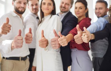 Kendine güvenen iş adamlarından oluşan bir grup. Kameraya bakan, işaret eden ve gülümseyen kadın ve erkekler. Şirket çalışanlarının ekibi ofiste birlikte duruyor. Takım çalışması ve başarı kavramı.