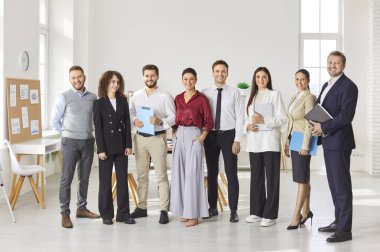Bir grup iş adamı kameraya bakıp içeride gülümseyen kadınlar ve erkekler. Resmi kıyafetler içindeki şirket çalışanları ya da bir grup çalışanın ofiste sırayla durması. Takım çalışması konsepti