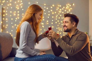 Benimle evlenir misin? Aşık bir çift romantik bir akşamda sürprizlerin tadını çıkarıyor. Mutlu genç adam kız arkadaşına altın nişan yüzüğü vermeyi teklif ediyor. Gülümseyen kadın evlilik teklifi alıyor ve kabul ediyor.