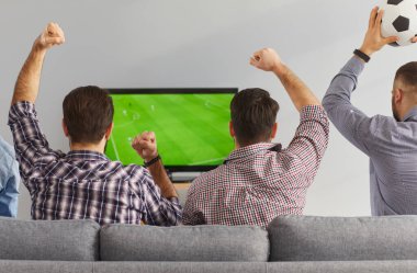 Erkekler televizyonda canlı yayında futbol maçı izliyor. Heyecanlı erkek arkadaşlar rahat koltukta oturup ilginç futbol şampiyonası izliyorlar, tezahürat yapıyorlar, bağırıyorlar ve en sevdikleri takımı destekliyorlar.