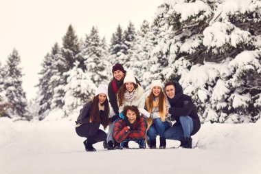 Kış ormanlarında yürürken kameraya gülümseyen genç ve gülen kadınlar ve erkekler