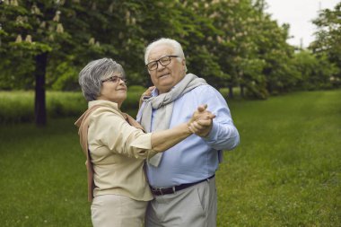 Parkta dans eden olgun çifti severek dışarıda geçirin. Romantik Kafkas aşığı büyükanne ve büyükbabası ormanda eğleniyor. Sağlık hizmetleri yaşam tarzı emeklilik kavramı