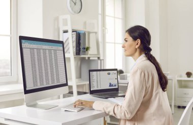 Teftiş, muhasebe ya da mali raporlar yapan bir kızın geniş ekrana baktığı yan görüntüler. Çekici genç bir kadın, iş yerindeki parlak ofiste oturuyor. Masasında, pencerenin önünde dizüstü bilgisayarla..