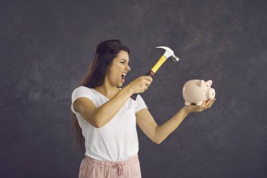 Siyah stüdyo geçmişi olan çılgın Latin bir kadın, paraya ihtiyacı olan çekiç kırma kumbarasını elinde tutuyor. Kızgın, öfkeli, çaresiz, bin yıllık kadın para için kumbarayı soyuyor. Finans, tasarruf kavramı.
