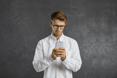 Man having problem with mobile app and looking at phone screen with unsatisfied discontent confused face expression. Young guy gets negative money balance notification on his modern cellphone