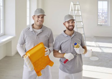 İki erkek ressamdan oluşan bir ekip yeni bir yapı planlıyor, tepsi ve boya rulosu tutuyor, evin duvarlarını boyuyor, tadilat ve yenileme üzerinde çalışıyor. Yenileme ve yeniden yapılandırma kavramı