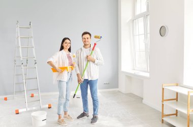 Mutlu evli genç çift yeni bir ev onarımı planlıyor, mutlu koca ve eş iç dekorasyondan zevk alıyor, duvarda çizimler yapıyor, birlikte resim yapıyor, mutlu aile hayatı için ev dekorasyonu yapıyor. 