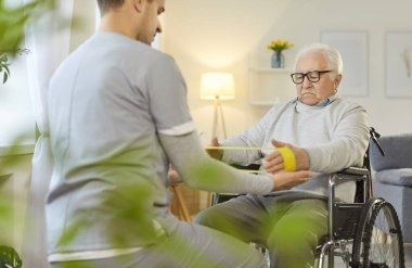 Tekerlekli sandalyedeki son sınıf öğrencisi elastik bant egzersizleri tıbbi kardeş, danışman hemşirelik, yaşlı, doktor ve yaşlı hasta rehabilitasyonuna yardım eden erkek hasta bakıcılarının sağlık ve sosyal hizmetleri