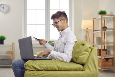 Genç adam çalışmak ya da çalışmak için dizüstü bilgisayar kullanıyor. Üniversite ya da üniversite öğrencisi gözlüklü, evdeki koltukta oturmuş bilgisayar ekranına bakıyor, video konuşmasında bir şeyler tartışıyor. Çevrimiçi eğitim kavramı