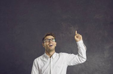 Siyah stüdyo arka planındaki heyecanlı beyaz adam boş fotokopi alanındaki nokta gösterisine bak. Gözlüklü, gülen milenyum erkeği promosyon indirimi için iyi bir indirim öneriyor..