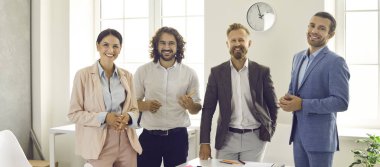 Modern bir iş merkezindeki bir toplantıda kendinden emin, arkadaş canlısı, mutlu ve başarılı dört iş ortağının portresi. Başarılı takım çalışması kavramı.