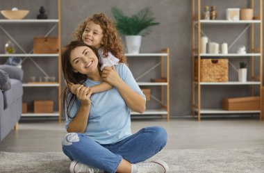 Küçük, mutlu bir kızın portresi. Sarılıp kucaklaşmak. Beyaz bir annenin evde oynaması. Minnettar gülümseyen altıncı yaş kızının sevgi dolu annesini kucaklaması neşeli bir rahatlama hissi veriyor. Annelik kavramı.