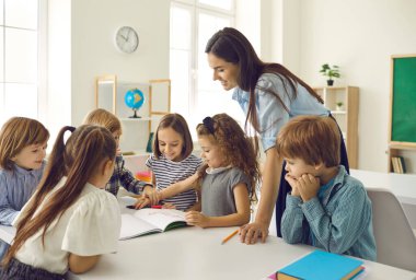 Bir grup çocuk, o küçük kızın gösterdiği fotoğrafa bakıyor. Mutlu okul öğretmenleri ve öğrencileri ilginç dersler alırlar, yeni şeyler öğrenirler, tartışırlar, modern sınıfta yaratıcı projeler üzerinde çalışırlar.
