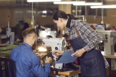 Kadın kalite kontrol müdürü, iş yerinde çalışan ayakkabı imalatçısıyla konuşuyor. Kadın yönetici ve zanaatkar birlikte çalışıyor. Ayakkabı fabrikası, ayakkabı endüstrisi ve manufactory.