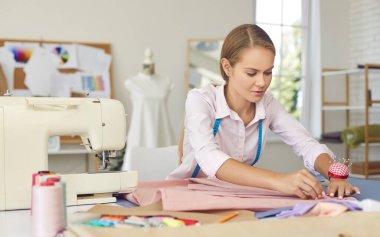 Genç beyaz kadın terzi moda tasarım stüdyosu dikiyor. Atölyedeki kadın tasarımcı ya da terzi tasarımcı elbise koleksiyonu. Tarz, terzilik, iş yeri. Hobi, iş konsepti.