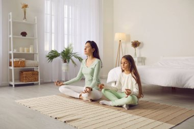 Günün iyi bir başlangıcı için aile yoga yapıyor. Anne ve çocuk evde sakin bir sabahta yoganın tadını çıkarıyorlar. Huzurlu, sakin bir anne ve sakin bir çocuk yatak odasındaki çapraz bacaklı Asana 'da meditasyon yapıyor.