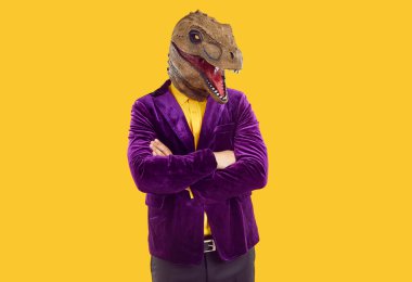 Dinozor maskeli komik müsrif adamın portresi katlanmış ellerle rahatça poz veriyor. Dinazor başlıklı tanınmayan bir adam turuncu arka planda modaya uygun kadife ceket giyiyor. Pankart.
